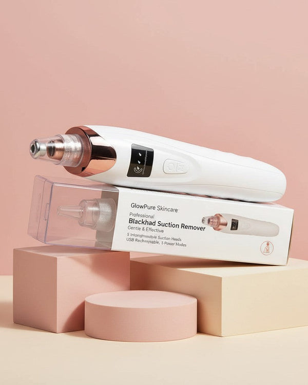 My Glam Room 5-in-1 electric blackhead remover vacuum with white and rose gold finish resting on its product box.