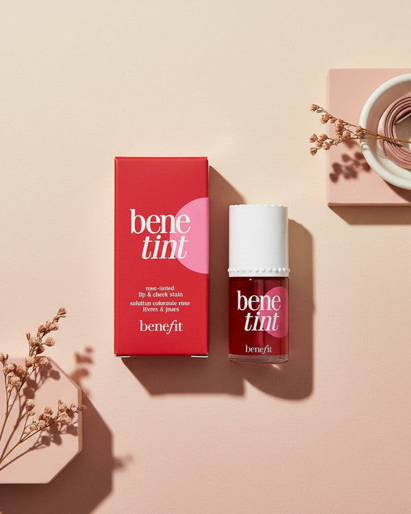 My Glam Room Benefit Bene Lip & Cheek Tint in a red bottle with matching box on a minimalist beige background.