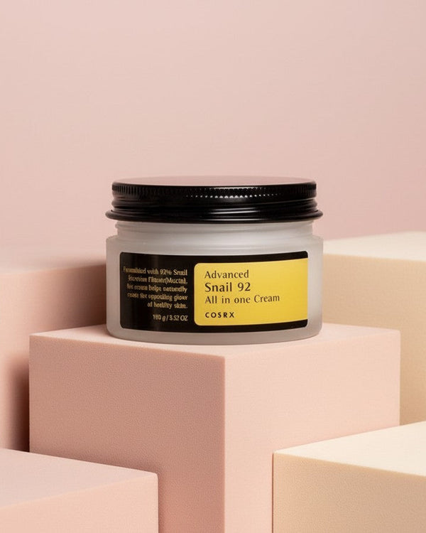 My Glam Room Cosrx Advanced Snail 92 All in One Cream in a frosted glass jar on pastel geometric blocks