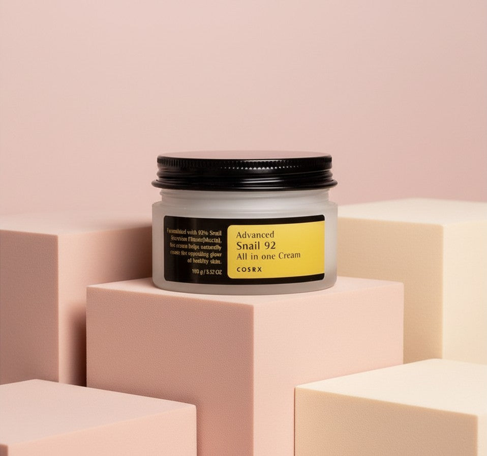 My Glam Room Cosrx Advanced Snail 92 All in One Cream in a frosted glass jar on pastel geometric blocks