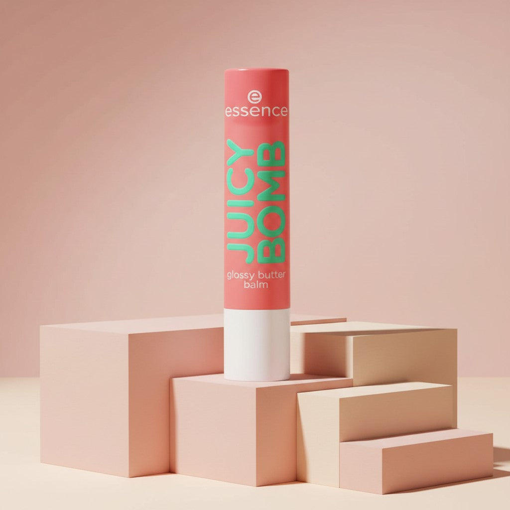 My Glam Room essence juicy bomb lip butter balm in a coral tube standing on geometric blocks against a pink background
