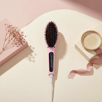 My Glam Room fast hair straightener brush in pastel pink with black bristles, displayed on a minimalist studio set.