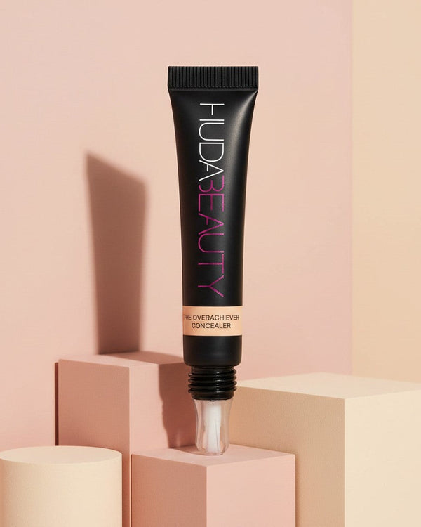 My Glam Room HUDA Beauty The Overachiever full coverage concealer in a black squeeze tube with applicator tip.