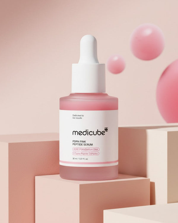 My Glam Room Medicube PDRN Pink Peptide Serum in a glass dropper bottle on geometric platforms with pink spheres.