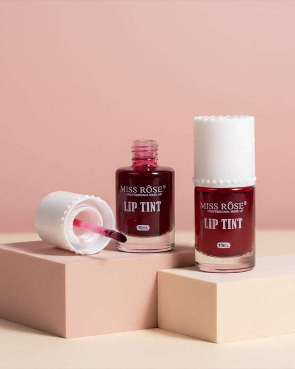 My Glam Room Miss Rose deep red lip and cheek tint in glass bottles with white caps on beige display blocks