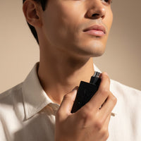 Man applying My Glam Room YSL MYSELF Le Parfum from a sleek black bottle against a neutral studio background