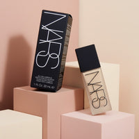 My Glam Room Nars All Day Luminous Foundation bottle and black box packaging on geometric pastel display blocks