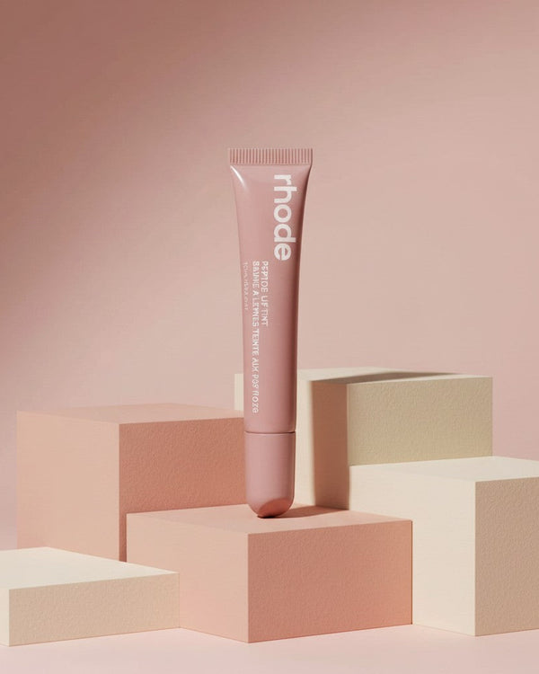 My Glam Room rhode Peptide Lip Tint in Toast shade, a neutral beige lip treatment in a squeeze tube on geometric blocks