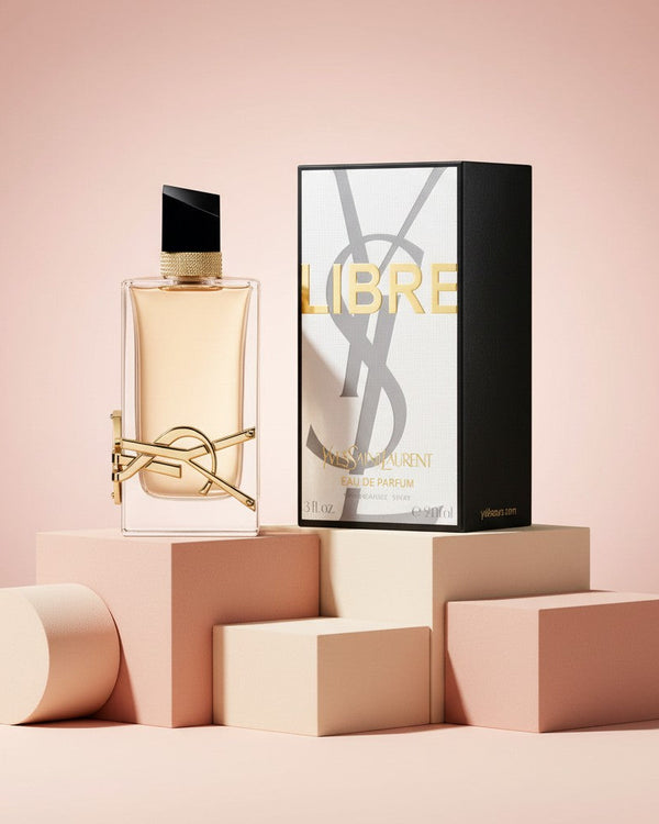 My Glam Room YSL Libre Le Perfume bottle and box displayed on geometric pedestals against a soft pink background.